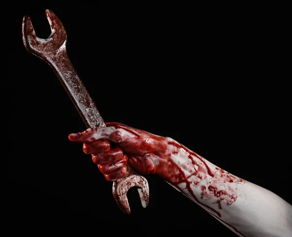 Bloody hand holding a big wrench, bloody wrench, big key, bloody theme, halloween theme, crazy mechanic, murderer, psycho, violence, zombies, black background, isolated, revolution — Stock Photo, Image