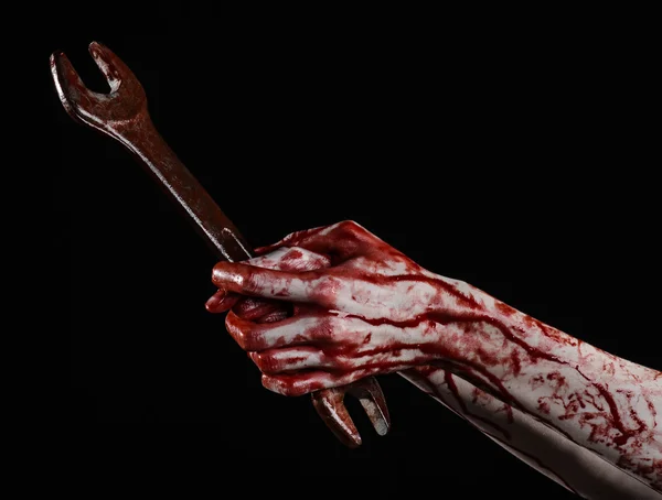 Bloody hand holding a big wrench, bloody wrench, big key, bloody theme, halloween theme, crazy mechanic, murderer, psycho, violence, zombies, black background, isolated, revolution — Stock Photo, Image