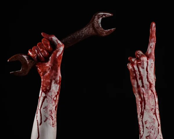 Bloody hand holding a big wrench, bloody wrench, big key, bloody theme, halloween theme, crazy mechanic, murderer, psycho, violence, zombies, black background, isolated, revolution — Stock Photo, Image