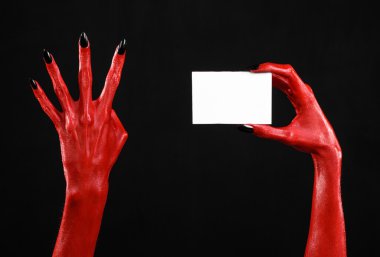 Halloween Tema: kırmızı şeytan el siyah çivi siyah bir arka plan üzerinde boş bir beyaz kart tutan