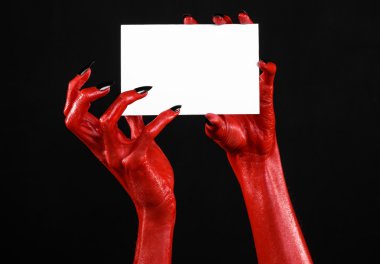 Halloween Tema: kırmızı şeytan el siyah çivi siyah bir arka plan üzerinde boş bir beyaz kart tutan