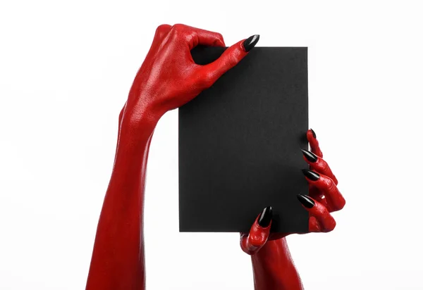Thème d'Halloween : Main du diable rouge avec des ongles noirs tenant une carte noire vierge sur un fond blanc — Photo