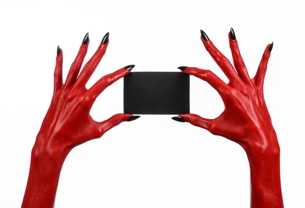 Tema de Halloween: Mano roja del diablo con clavos negros sosteniendo una tarjeta negra en blanco sobre un fondo blanco — Foto de Stock