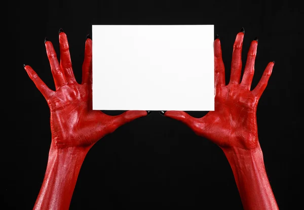 Halloween theme: Red devil hand with black nails holding a blank white card on a black background — Stock Photo, Image