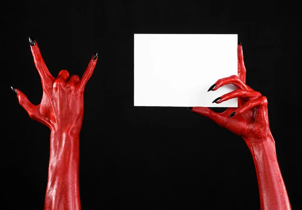 Tema de Halloween: Mano roja del diablo con clavos negros sosteniendo una tarjeta blanca en blanco sobre un fondo negro —  Fotos de Stock