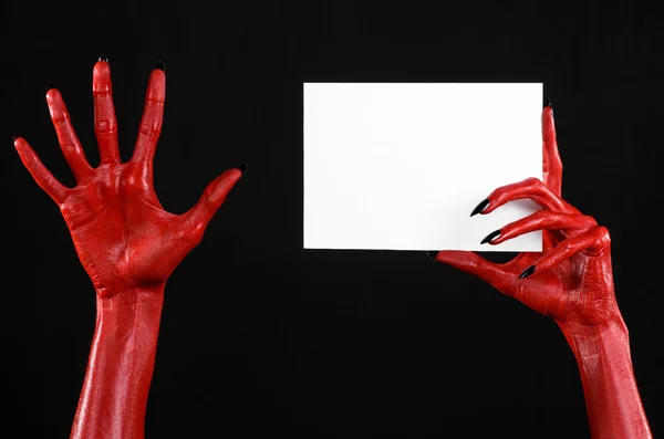 Tema di Halloween: mano del diavolo rosso con chiodi neri che tengono una carta bianca vuota su uno sfondo nero — Foto Stock