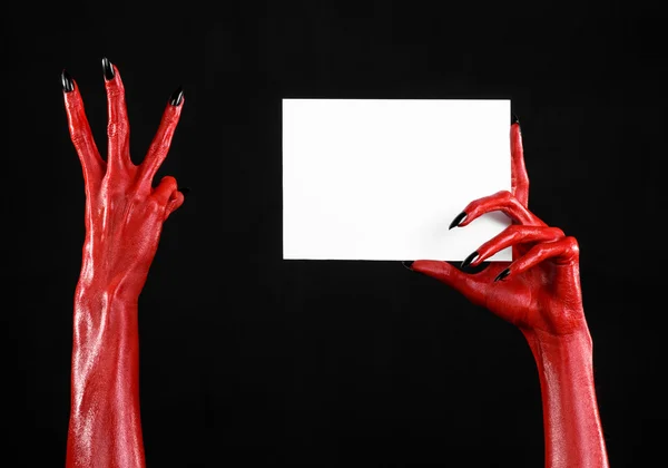 Thème d'Halloween : Main du diable rouge avec des ongles noirs tenant une carte blanche vierge sur un fond noir — Photo