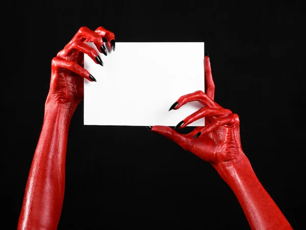 Tema de Halloween: Mano roja del diablo con clavos negros sosteniendo una tarjeta blanca en blanco sobre un fondo negro — Foto de Stock