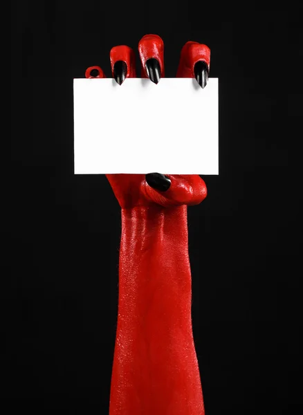 Tema de Halloween: Mano roja del diablo con clavos negros sosteniendo una tarjeta blanca en blanco sobre un fondo negro — Foto de Stock