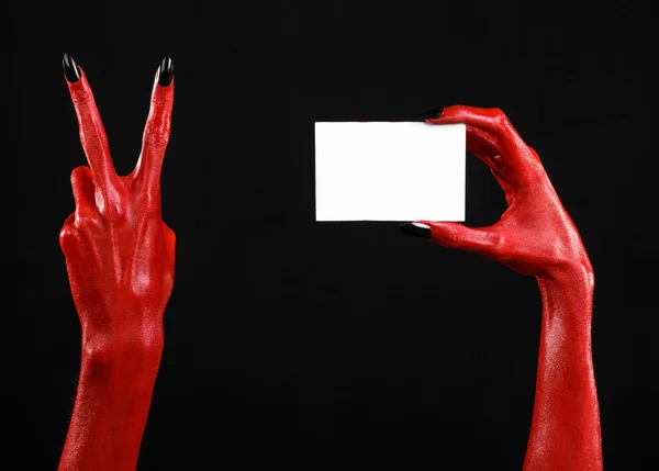 Halloween tematu: czerwony diabeł ręcznie z czarnym paznokcie gospodarstwa puste karty białe na czarnym tle — Zdjęcie stockowe