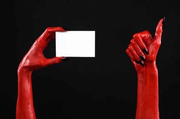 Halloween-tema: röda djävulen hand med svart naglar håller ett tomt vitt kort på svart bakgrund — Stockfoto