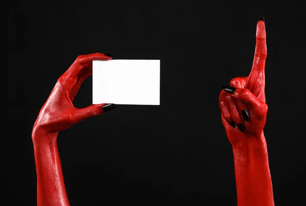 Tema de Halloween: Mano roja del diablo con clavos negros sosteniendo una tarjeta blanca en blanco sobre un fondo negro —  Fotos de Stock