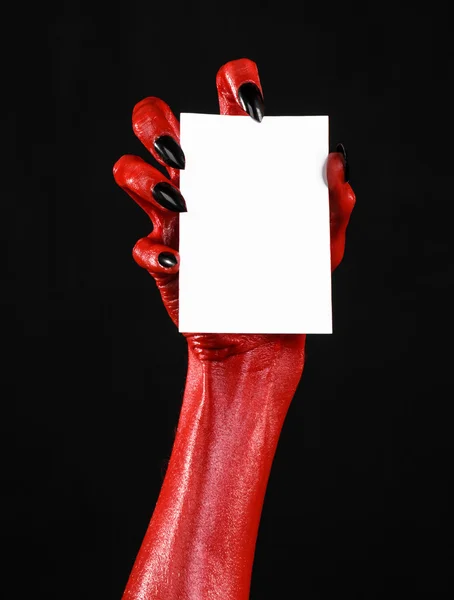 Tema de Halloween: Mano roja del diablo con clavos negros sosteniendo una tarjeta blanca en blanco sobre un fondo negro — Foto de Stock