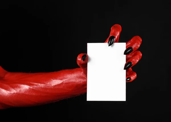 Thème d'Halloween : Main du diable rouge avec des ongles noirs tenant une carte blanche vierge sur un fond noir — Photo