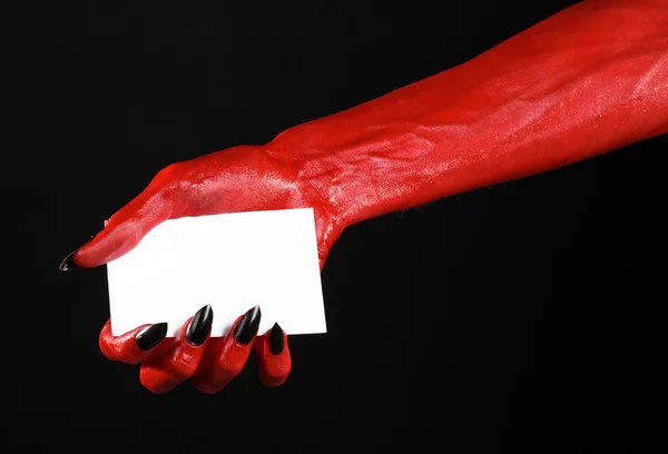 Tema de Halloween: Mano roja del diablo con clavos negros sosteniendo una tarjeta blanca en blanco sobre un fondo negro — Foto de Stock