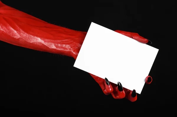Тема Хеллоуїна: рука червоного диявола з чорними цвяхами, що тримає порожню білу картку на чорному тлі — стокове фото