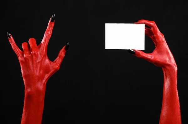 Tema de Halloween: Mano roja del diablo con clavos negros sosteniendo una tarjeta blanca en blanco sobre un fondo negro —  Fotos de Stock