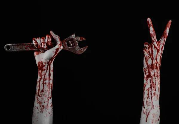 Тема Хэллоуина: окровавленная рука с большим гаечным ключом на черном фоне — стоковое фото
