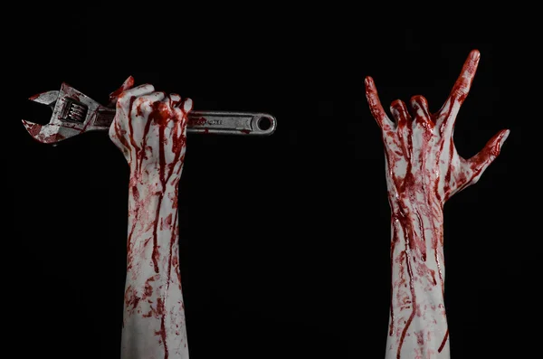 Halloween theme: bloody hand holding a big wrench on a black background — Stock Photo, Image