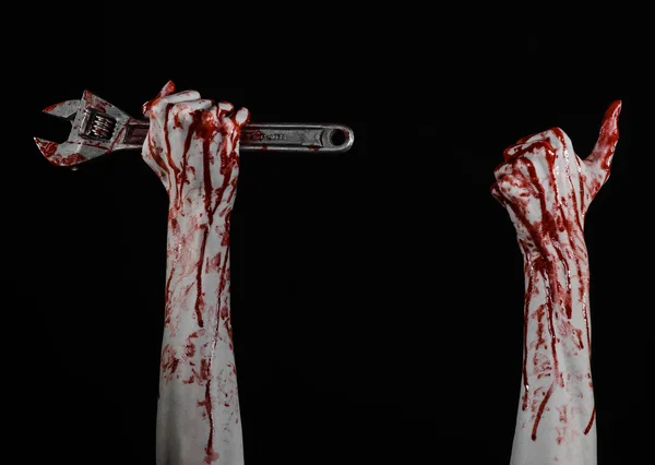 Halloween theme: bloody hand holding a big wrench on a black background — Stock Photo, Image