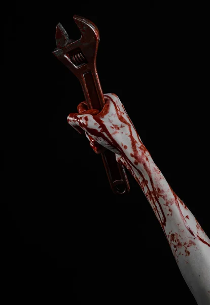 Halloween theme: bloody hand holding a big wrench on a black background — Stock Photo, Image