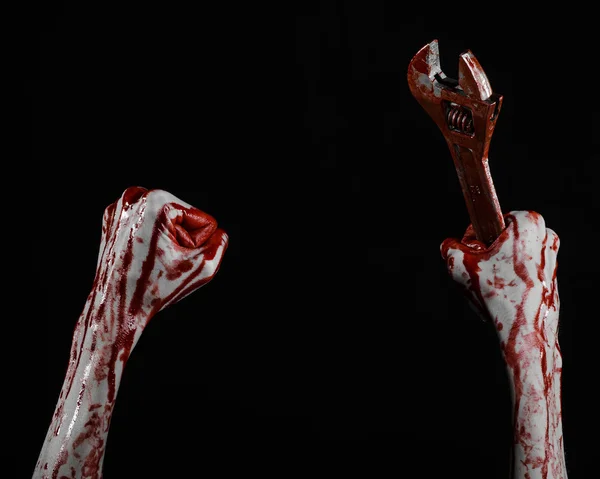 Halloween theme: bloody hand holding a big wrench on a black background — Stock Photo, Image