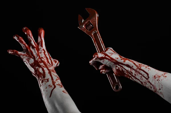 Halloween theme: bloody hand holding a big wrench on a black background — Stock Photo, Image