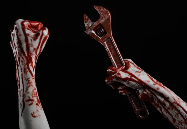 Halloween theme: bloody hand holding a big wrench on a black background — Stock Photo, Image