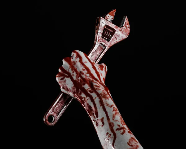 Halloween theme: bloody hand holding a big wrench on a black background — Stock Photo, Image