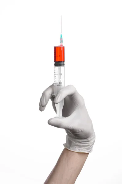 Läkarens hand håller en spruta, vita handskar handen, en stor spruta, medicinsk fråga läkaren gör en injektion, vit bakgrund, isolerade, vita handskar läkare, ebola test, röda medicinering Stockbild