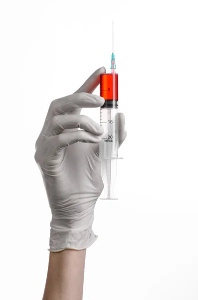 Doctor's hand met een injectiespuit, wit-gehandschoende hand, een grote spuit, medische kwestie, de arts maakt een injectie, witte achtergrond, geïsoleerde, witte handschoenen arts, ebola test, rode medicatie Stockfoto