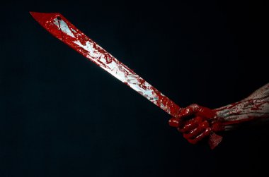 Bloody halloween theme: bloody hands holding a bloody machete isolated on black background in studio clipart