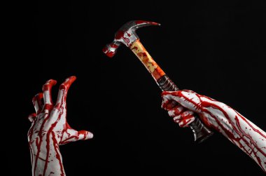 Bloody halloween theme: bloody hand holding a bloody hammer isolated on a black background