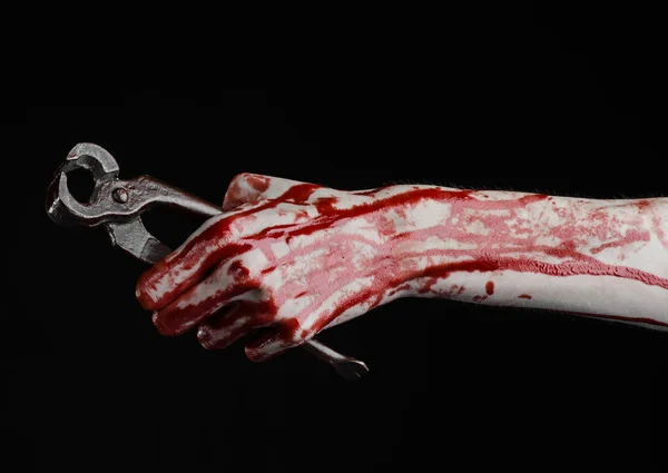 Halloween theme: bloody hand holding a pliers on a black background — Stock Photo, Image