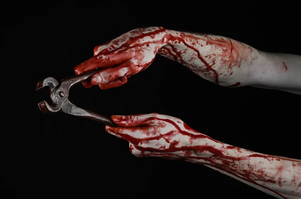 Halloween theme: bloody hand holding a pliers on a black background — Stock Photo, Image