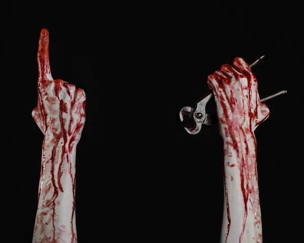 Tema de Halloween: Mano sangrienta sosteniendo un alicate sobre un fondo negro — Foto de Stock