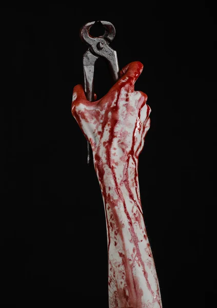 Tema de Halloween: Mano sangrienta sosteniendo un alicate sobre un fondo negro — Foto de Stock