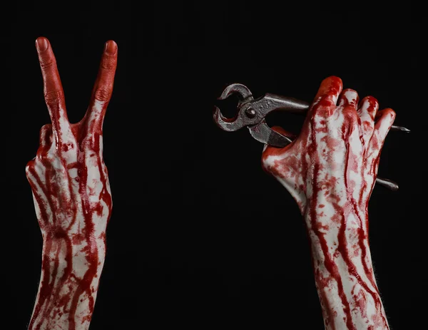 Halloween theme: bloody hand holding a pliers on a black background — Stock Photo, Image