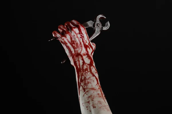 Тема Хэллоуина: кровавая рука, держащая плоскогубцы на черном фоне — стоковое фото