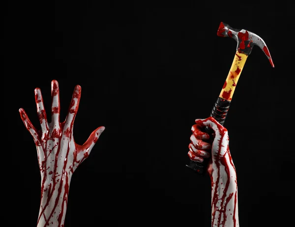 Blodiga halloween tema: blodiga handen håller en blodig hammare isolerad på en svart bakgrund — Stockfoto