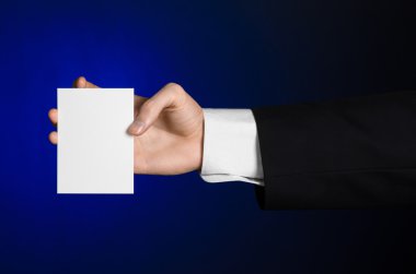 İş ve reklam Konu: elinde Studio izole koyu mavi zemin üzerine beyaz bir boş kartı tutan siyah elbiseli adam