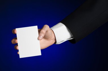 İş ve reklam Konu: elinde Studio izole koyu mavi zemin üzerine beyaz bir boş kartı tutan siyah elbiseli adam