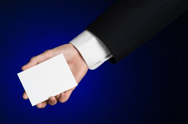 İş ve reklam Konu: elinde Studio izole koyu mavi zemin üzerine beyaz bir boş kartı tutan siyah elbiseli adam