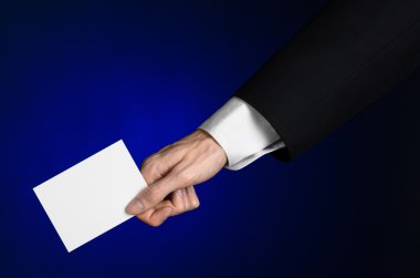 İş ve reklam Konu: elinde Studio izole koyu mavi zemin üzerine beyaz bir boş kartı tutan siyah elbiseli adam