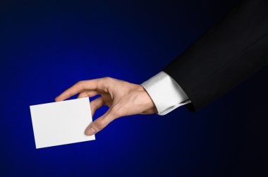 İş ve reklam Konu: elinde Studio izole koyu mavi zemin üzerine beyaz bir boş kartı tutan siyah elbiseli adam