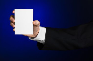 İş ve reklam Konu: elinde Studio izole koyu mavi zemin üzerine beyaz bir boş kartı tutan siyah elbiseli adam