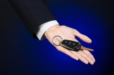 İş ve hediye Tema: araba satıcısı siyah elbiseli Studio koyu mavi arka plan üzerinde yeni bir araba için anahtarları tutan