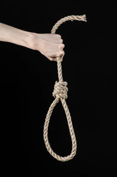 Lynching e suicidio tema: mano dell'uomo che tiene un cappio di corda per appendere su sfondo nero isolato — Foto Stock