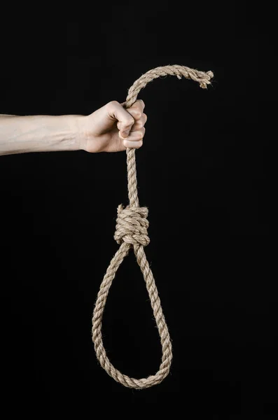 Лінчінг і тема самогубства: рука людини тримає петлю мотузки для повішення на чорному ізольованому фоні — стокове фото