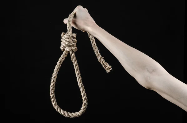 Lynčování a sebevražedné téma: izolovaná mužská ruka drží smyčku lana pro zavěšení na černém pozadí — Stock fotografie